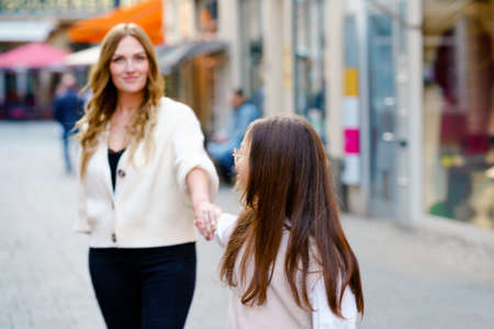 Young mother and school preteen girl making walk in the city. Happy family, woman and daughter with glasses enjoy time together. Love and support of parents. Happiness of mum and child.の写真素材