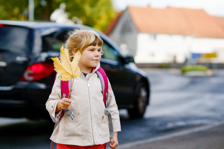 Cute little preschool girl on her first day going to playschool. Healthy happy child walking to...