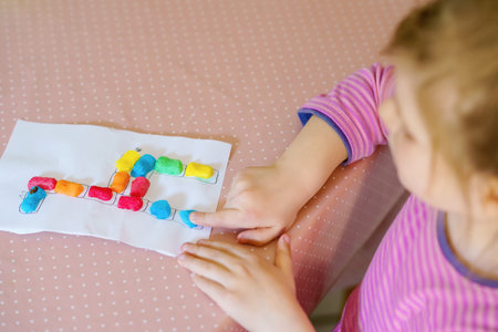 Little creative toddler girl making colorful giraffe with playmais. Active happy child having fun...