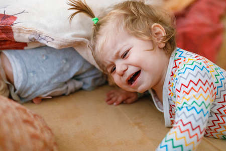 Cute upset unhappy toddler girl crying. Angry emotional child shouting. Portrait of kid with tears indoorsの写真素材