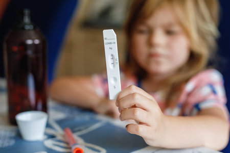 Covid-19 testing children. Sad Child holding self rapid test with positive result. Coronavirus...