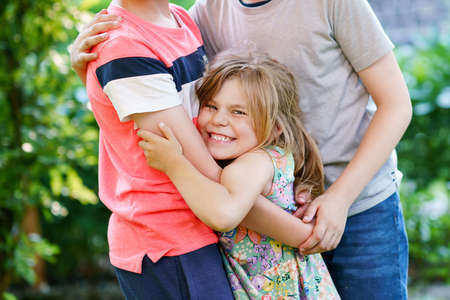 Portrait of three siblings children. Two kids brothers boys and little cute toddler sister girl having fun together in domestic garden. Happy healthy family playing, walking, active leisure on natureの写真素材