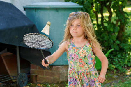 Cute little girl playing badminton outdoors on warm and sunny summer day. Preschool child having fun with outdoor activity and sportsの写真素材