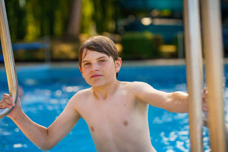 school kid boy ready to swim in the sport swimming pool. outoors on summer day. Sport activities for children. Training for competition. Child in the pool.の写真素材