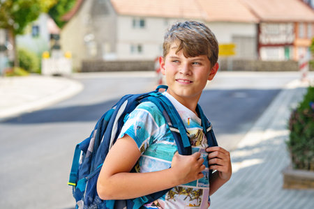 Happy little kid boy with satchel, walking. Schoolkid on the way to middle or high school. Excited...