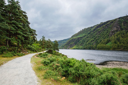 Idyllic view in Glendalough Valley, County Wicklow, Ireland. Mountains, lake and tourists walking...