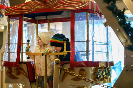Little preschool girl riding on ferris wheel carousel horse at Christmas funfair or market, outdoors. Happy toddler child having fun on traditional family xmas market in Germanyの写真素材