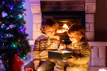 Cute toddler boys, blond twins playing together and opening surprise gift box on Christmasの写真素材