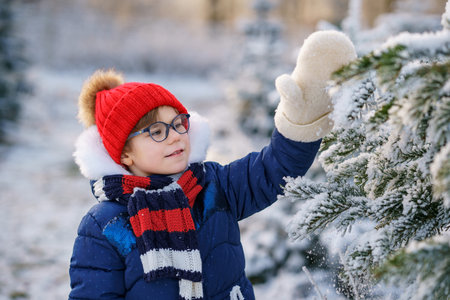 Small girl playing with snow. Happy preschool child in winter forest on snowy cold december day.の写真素材