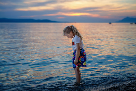 Little girl walking on beautiful ocean beach. Happy preschool child play by sunset on sea beach. Family vacations with children in summer.の写真素材