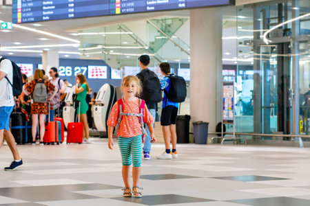 Little preschool girl at airport terminal. Happy child going on vacations by airplane. Smiling kid with passport and bag.の写真素材