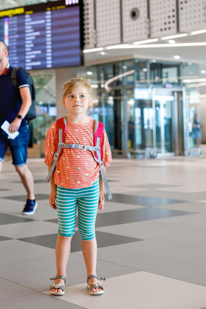 Little preschool girl at airport terminal. Happy child going on vacations by airplane. Smiling kid with passport and bag.の写真素材