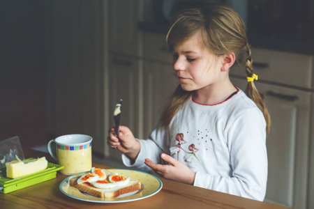 Little smiling girl have a breakfast at home. Preschool child eating sandwich with boiled eggs. Happy children, healthy food and meal.の写真素材