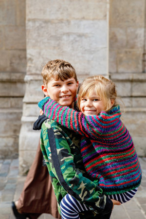 Two happy siblings, little girl and school boy together. Smiling brother and sister, best friends. Little kid with sister on his back. Family in love.の写真素材