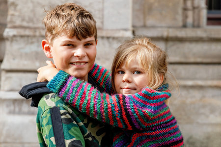 Two happy siblings, little girl and school boy together. Smiling brother and sister, best friends. Little kid with sister on his back. Family in love.の写真素材