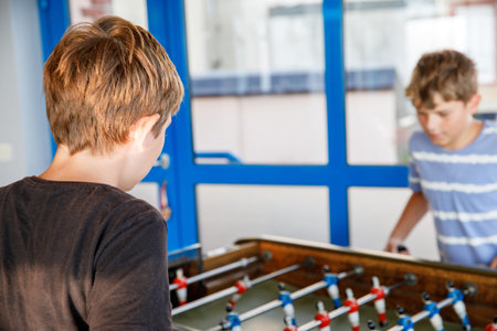 Two smiling school boys playing table soccer. Happy excited children having fun with family game...