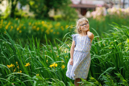 Portrait of a cute preschool girl with eye glasses outdoors in park. Happy funny child on sunny summer day.の写真素材
