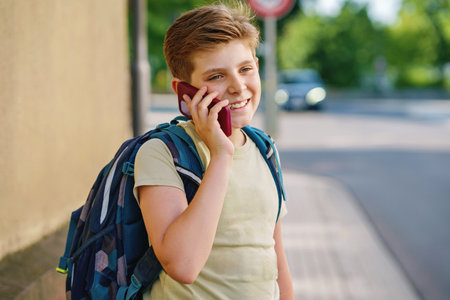 Handsome teenager boy speaking on the smartphone. Preteen child with mobile cell phone on the street on the way to school.の写真素材