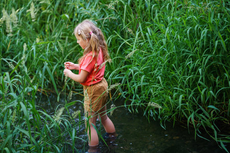 A Happy Girl Embraces the Joys of Childhood as She Explores a Summer Creek, Immersing Herself in Natures Wonders and Playful Discoveries. Preschool Child and Summertime.の写真素材