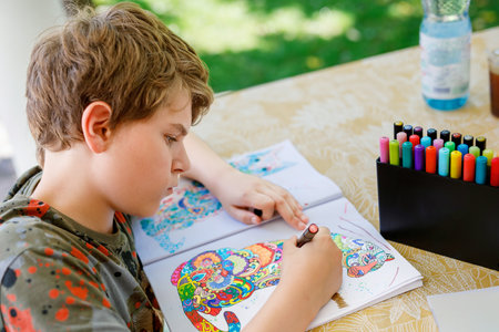 Preteen School Boy Drawing with Felt Pens. Back to School. Caucasian Little Schoolboy Drawing Picture at Home. Hobbies, education conceptの写真素材