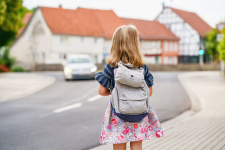 Little Preschool Girl on the Way to School. Healthy Happy Child Walking to Nursery School and Kindergarten. Smiling Child with Eyeglasses and Backpack on the City Street, Outdoors. back to schoolの写真素材