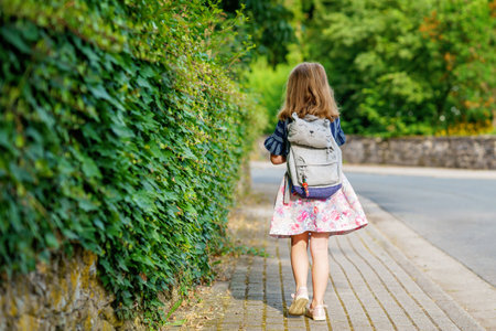 Little Preschool Girl on the Way to School. Healthy Happy Child Walking to Nursery School and Kindergarten. Smiling Child with Eyeglasses and Backpack on the City Street, Outdoors. back to schoolの写真素材
