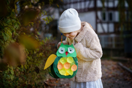 Little preschool kid girl holding selfmade traditional owl lanterns with candle for St. Martin procession. child happy about children and family parade in kindergarten. German tradition Martin parade.の写真素材
