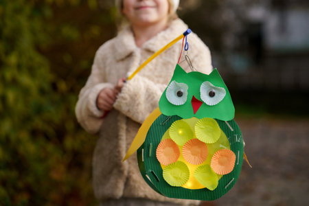 Little preschool kid girl holding selfmade traditional owl lanterns with candle for St. Martin procession. child happy about children and family parade in kindergarten. German tradition Martin parade.の写真素材