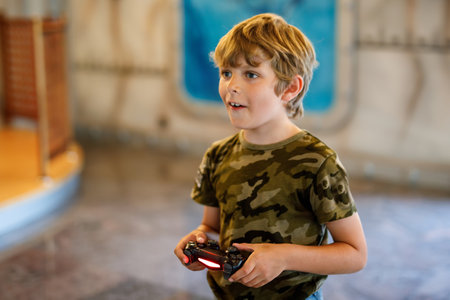 Happy positive boy having fun playing with video console. Little chool child holding joystick. Indoor computer games for children and kids.の写真素材