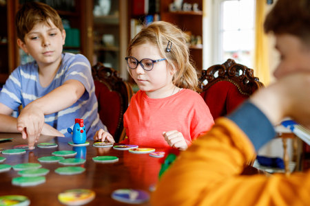 Family playing board game at home. Kids play strategic game. Little sister girl and two school brothers boys. Fun indoor activity. Siblings bond. Educational toys.の写真素材