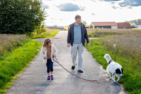 Father, little preschool girl and family dog walking outdoors. Middle-aged man and cute daughter with pet. Happy child and dad together, having funの写真素材