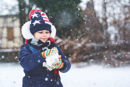 Cute little preschool girl outdoors in winter park . Adorable healthy happy child playing and having...