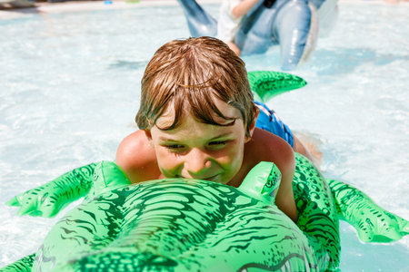 Portrait of happy little kid boy in the pool and having fun on family vacations in a hotel resort. Healthy child playing in water, swimming and splashing.の写真素材