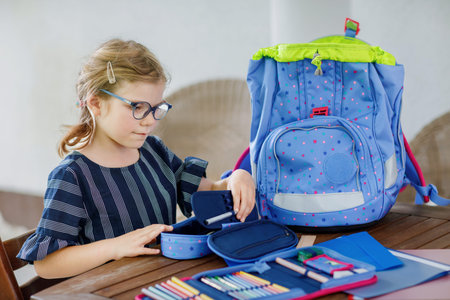 Happy smiling girl preparing for school her backpack. First day of school. Back to school concept....
