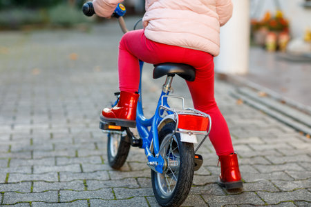 Little preschool girl riding bike. Kid on bicycle outdoors. Happy child enjoying bike ride on her way to school on warm summer day. Preschooler learning to balance on bicycle in safe helmet.の写真素材