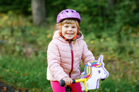 Child riding balance bike. Kids on bicycle in sunny forest. Little girl enjoying to ride glider bike on warm day. Preschooler learning to balance on run bicycle in safe helmet. Sport activityの写真素材