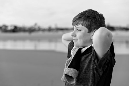 Happy cheerful teenager standing on beach at sunset. happy preteen boy smiling at the camera. Kid on family vacation at the sea.の写真素材