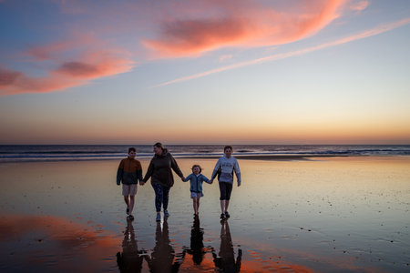 Portrait silhouettes of three children and mum happy kids with mother on beach at sunset. happy family, woman, two school boys and one little preschool girl. Siblings having fun together. Bondingの写真素材
