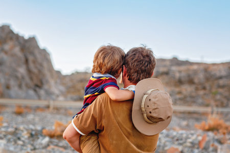 Father and son traveling through West of USA in Grand Canyon. Happy little child and young man. Dad holding boy on arms., looking at mountains.の写真素材