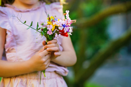 Happy toddler girl holding a bouquet of wildflowersの写真素材