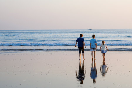 Three children, happy siblings on ocean beach at sunset. happy family, two school boys and one little preschool girl. Brothers and sister having fun, Spain, Costa del Solの写真素材