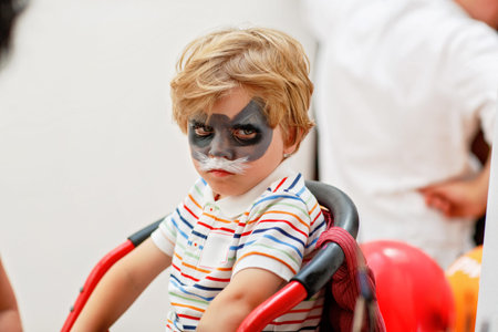 Beautiful little kid boy with face painted with animal or cat, on a birthday party. happy child...
