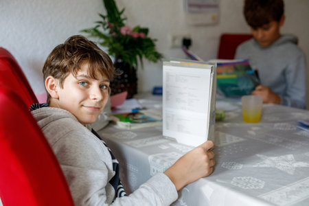 Two teenagers boys learning at home. Teenage students with book, happy kid. Education concept. Children, friends and brothers doing school homeworkの写真素材