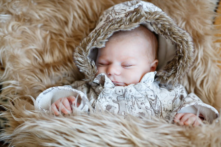 Portrait of newborn baby in warm winter clothes. Beautiful cute girl in warm overall, cap. Peaceful...