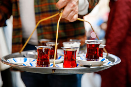 Turkish tea in traditional glass mugs on a metal tray. Street vendor selling hot tea in Istanbul, Turkey, Grand Bazaar.の写真素材