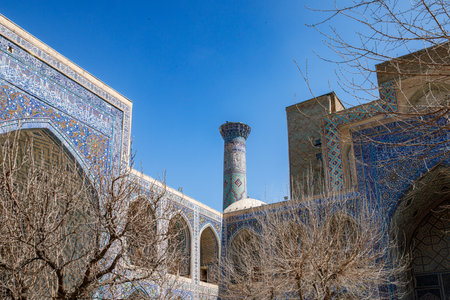 Part of Registan Square in Samarkand, Uzbekistan, a historic architectural ensemble featuring three stunning madrasas with intricate mosaic designs, domes, and minarets under a bright blue skyの写真素材