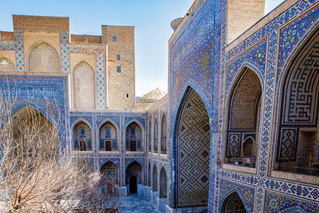 Part of Registan Square in Samarkand, Uzbekistan, a historic architectural ensemble featuring three stunning madrasas with intricate mosaic designs, domes, and minarets under a bright blue skyの写真素材