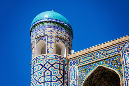 Part of Registan Square in Samarkand, Uzbekistan, a historic architectural ensemble featuring three stunning madrasas with intricate mosaic designs, domes, and minarets under a bright blue skyの写真素材