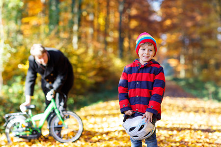 Little kid boy and father with bicycle in autumn forestの写真素材