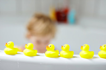 Adorable cute little toddler girl taking bath in bathtub. Happy healthy baby child playing with rubber gum toys and having fun. Washing, cleaning, hygiene for children.の写真素材